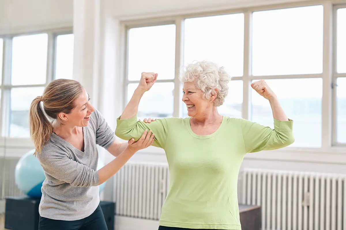 Shot of physiotherapist helping patient to do exercise on fitness ball in physio room.